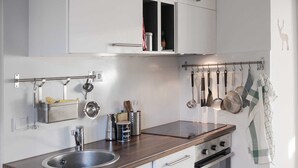 A modern kitchen with a stainless steel sink, a built-in oven, and a hanging pot rack. - Haushimmelblau, Germany (Sankt Andreasberg)