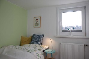 A bedroom with a bed, a window, a radiator, and a framed picture on the wall. - Haushimmelblau, Germany (Sankt Andreasberg)