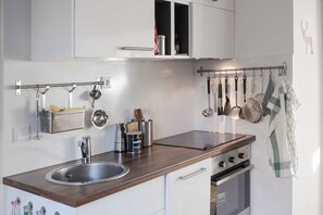 A modern kitchen with a stainless steel sink, a built-in oven, and a hanging pot rack. - Haushimmelblau, Germany (Sankt Andreasberg)