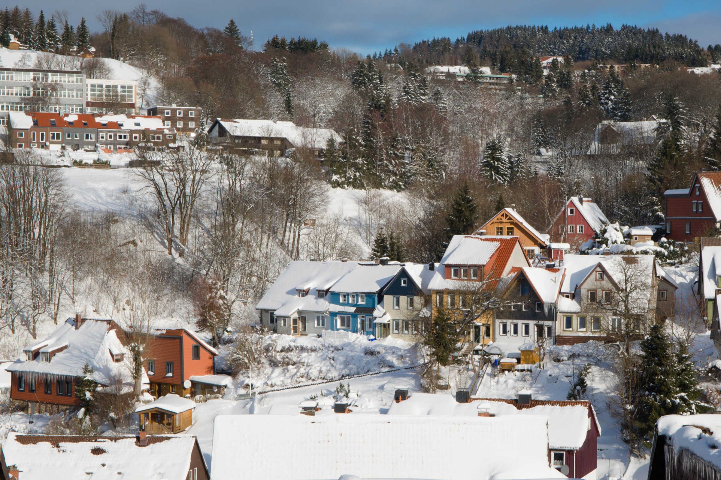 Área residencial coberta de neve, com casas e um edifício ao fundo.