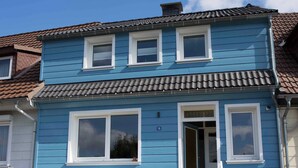 A two-story building with a blue exterior, white window frames, and a tiled roof. - Haushimmelblau, Germany (Sankt Andreasberg)