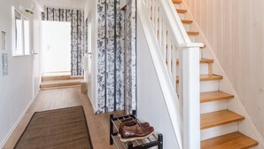 A staircase with wooden steps and white railings, leading to a landing with a door and a wall with vertical patterned wallpaper. - Haushimmelblau, Germany (Sankt Andreasberg)