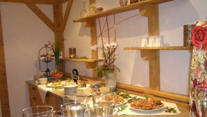 En morgenmadsbuffet med forskellige retter, vandglas og en blomsterdekoration.