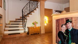 A staircase with wooden steps and black metal railings, a wooden cabinet with a vase of flowers, and a framed photograph on the wall. - Apartment 16 - Liedschreiber GbR Guesthouse and Vacation Rentals (Kreuth)