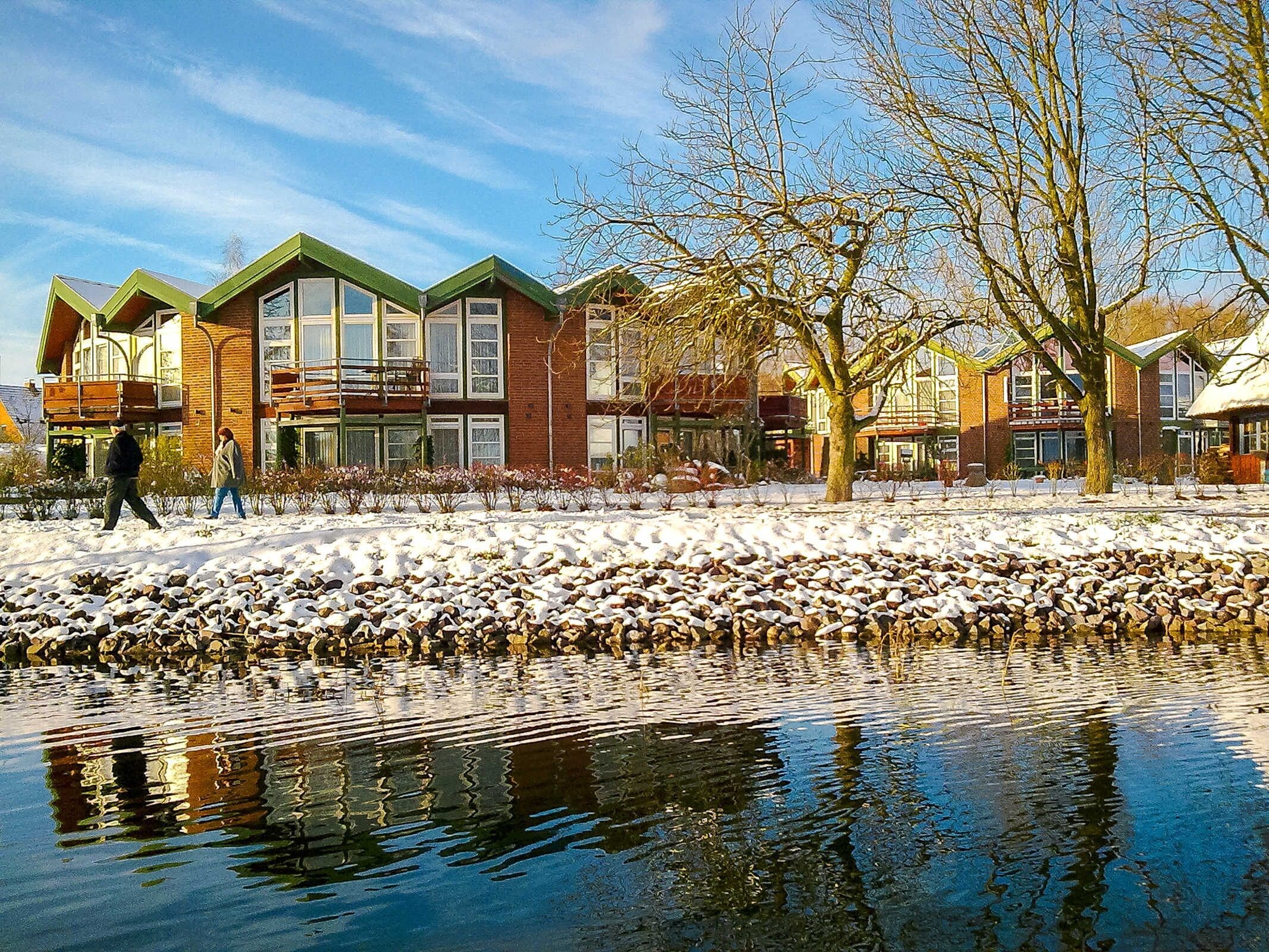 Una hilera de edificios modernos con amplios ventanales y suelo cubierto de nieve.