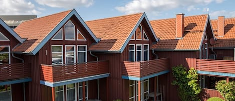 Un moderno edificio residencial con varios balcones, ventanas amplias y un jardín bien cuidado.