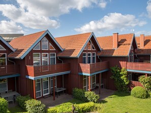 Een modern woongebouw met meerdere balkons, grote ramen en een verzorgde tuin.