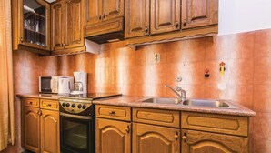Una cocina con gabinetes de madera, estufa, microondas y lavamanos.