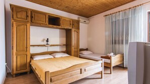 Una habitación con una cama grande de madera, una cama más pequeña, un televisor y un armario.