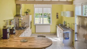 Una cocina con una mesa de madera, una estufa a gas, un lavamanos y una ventana con vistas al verdor.
