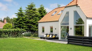 Una casa moderna con tejado inclinado, ventanas amplias y un césped bien cuidado.