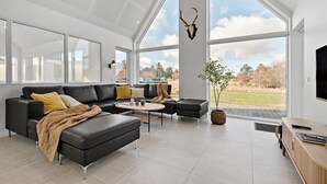 Una sala de estar moderna con un sofá de cuero negro, una mesita de centro y un ventanal con vistas al exterior.