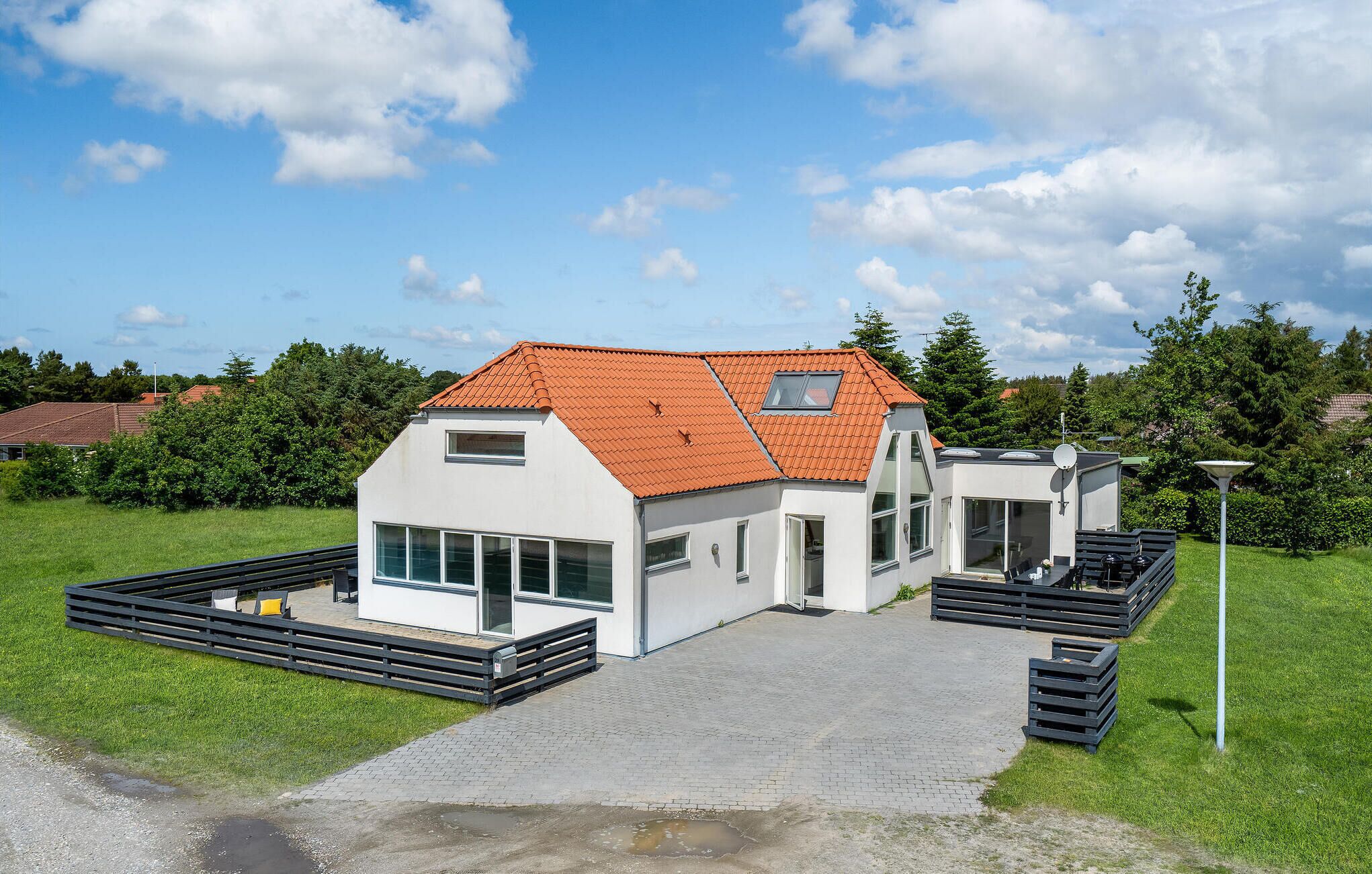 A modern house with a sloped roof, a large window, and a paved driveway.