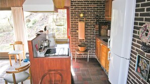 Une cuisine de taille réduite avec un mur en briques, un réfrigérateur blanc et un luminaire suspendu.