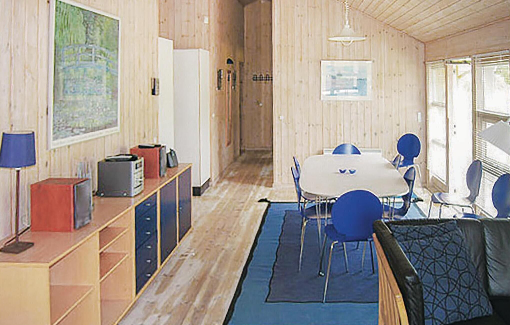 Une pièce avec un intérieur en bois, une table à manger avec des chaises, un canapé, une lampe et un meuble avec des tiroirs.