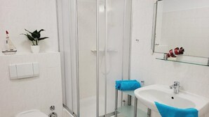 A bathroom with a glass-enclosed shower, a white sink, and a toilet. - (146) 2-room apartment - Apartment house Olymp (Kühlungsborn)