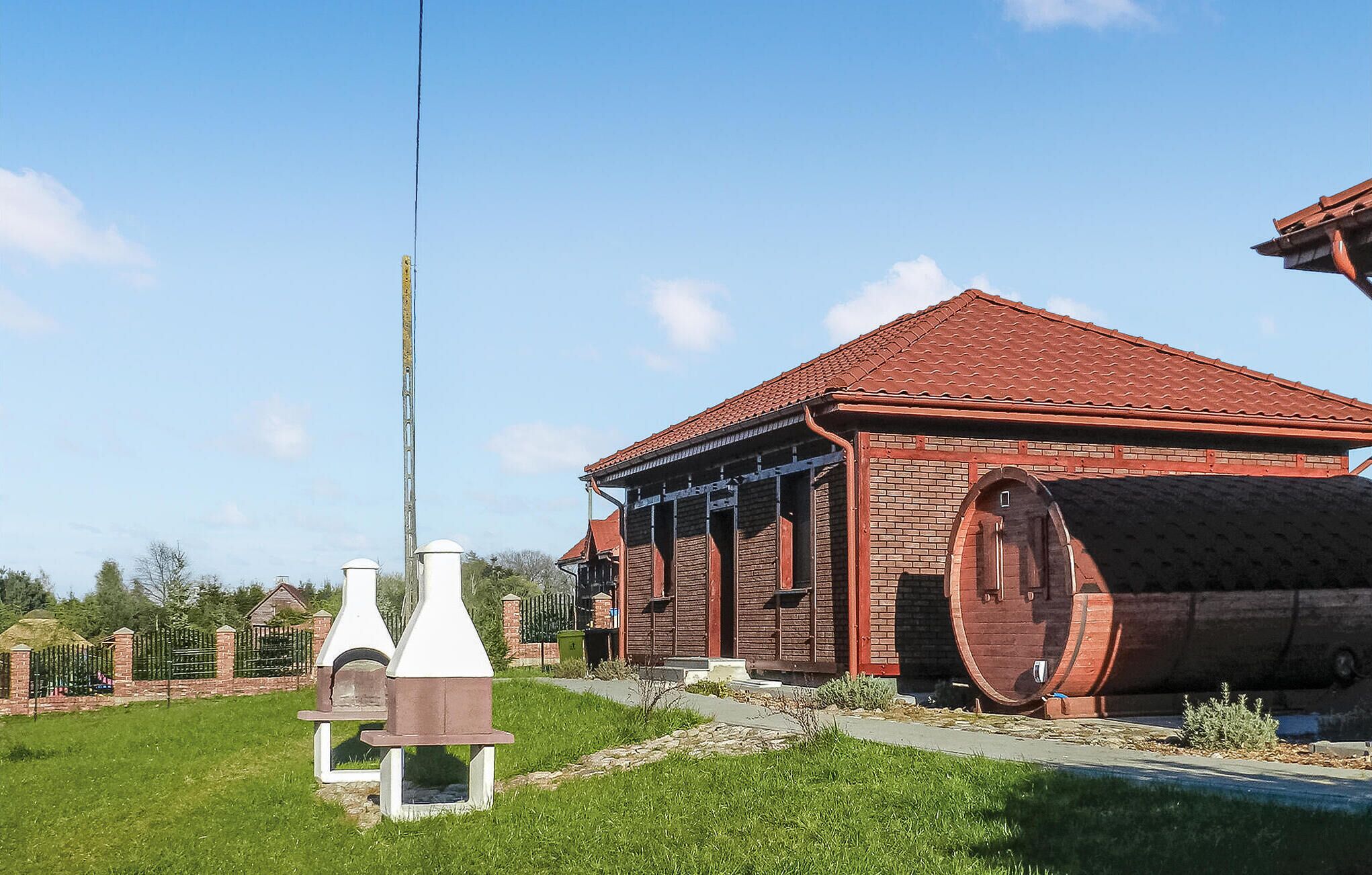 A brick building with a red-tiled roof, a large barrel, and a white structure with a chimney.