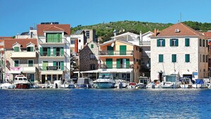 Uma cidade costeira com edifícios ao longo da orla, barcos atracados e um céu azul claro.