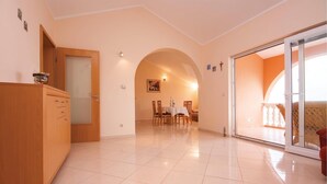 Um quarto amplo com área de jantar, um armário de madeira e uma porta de vidro deslizante para área externa.