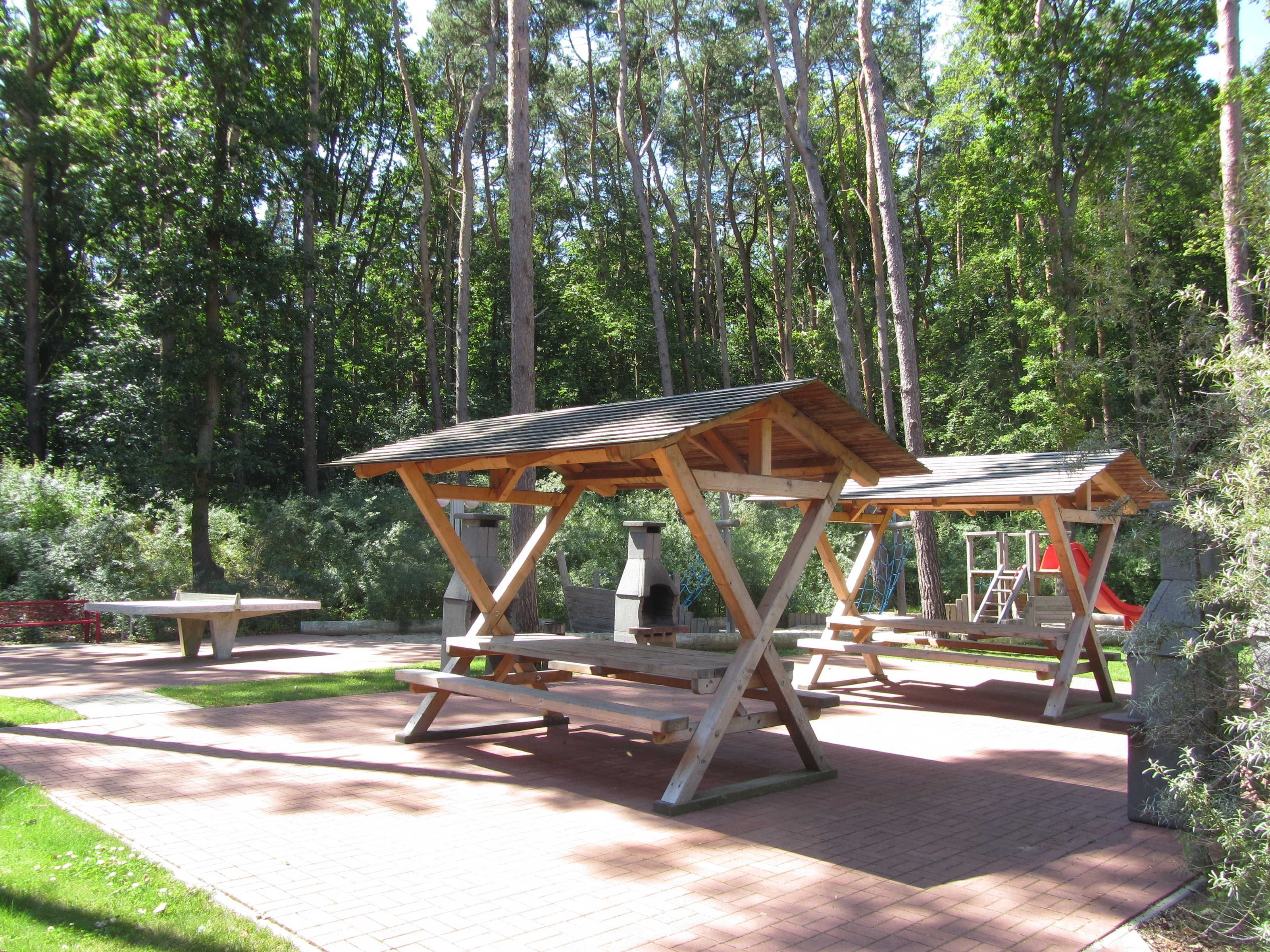 A picnic area with wooden shelters and benches in a forested park.
