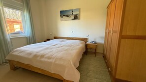 Ein Schlafzimmer mit Bett, Nachttischen, einer Lampe, einem Gemälde und einem Kleiderschrank.