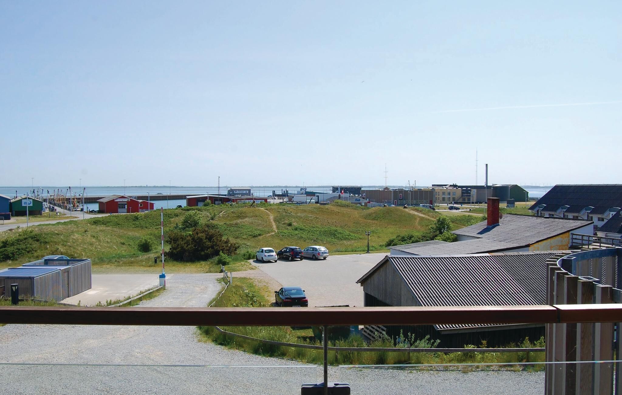 Ett industriområde vid kusten med byggnader, en grusväg och parkerade bilar.