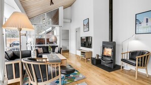 A modern living room with a fireplace, wooden furniture, and a large window. - Gorgeous home in Hasle with WiFi (Hasle)