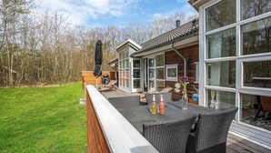 A wooden deck with outdoor furniture, a glass-enclosed patio, and a view of a forested area. - Gorgeous home in Hasle with WiFi (Hasle)