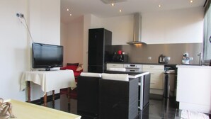 Een knus woongedeelte met een televisie, een bank, een eettafel, een keukenhoek met een magnetron en een kleine koelkast.