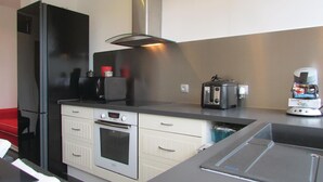 Een moderne keuken met een zwarte koelkast, een magnetron, een broodrooster en een koffieapparaat.