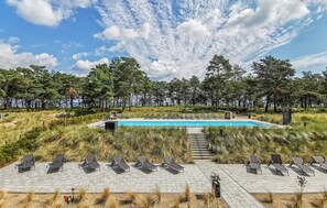 Área da piscina com espreguiçadeiras e vista para a floresta ao redor.