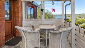 A covered patio with wicker furniture, a view of a lake, and a brick wall.
