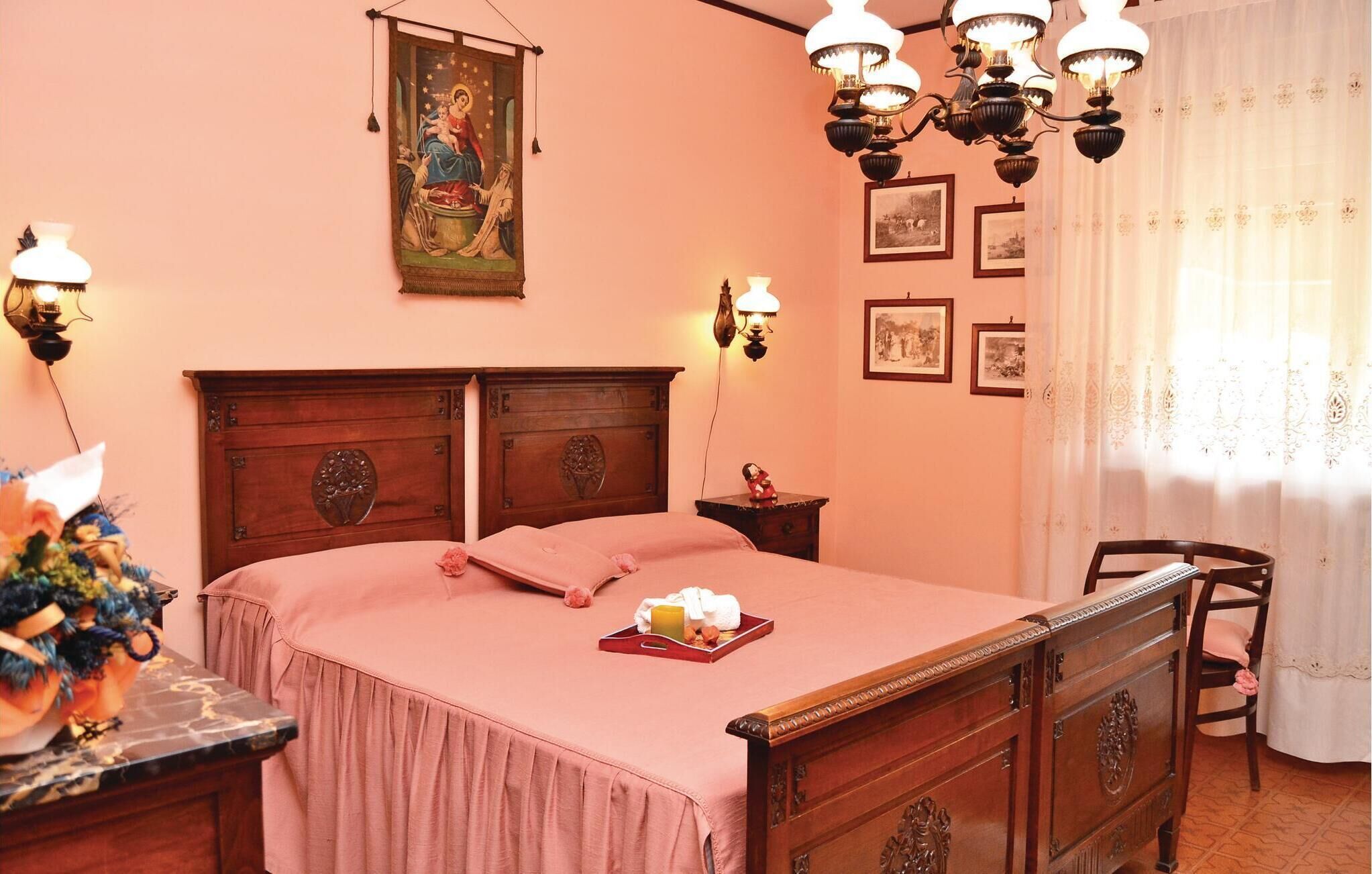 Une chambre à coucher avec un lit en bois, une table de chevet, une lampe et un tableau accroché au mur.