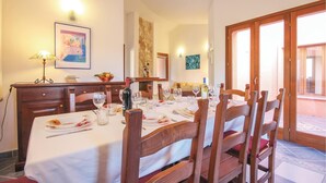 Un comedor con una mesa dispuesta para cuatro, sillas de madera, una araña y obras de arte en las paredes.
