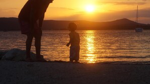 Un coucher de soleil sur une étendue d’eau, avec la silhouette d’une personne et d’un enfant.
