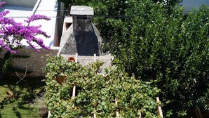 Un jardin agrémenté d’une structure en treillis soutenant des plantes grimpantes, entouré de plantes en pot et agrémenté d’un élément décoratif en pierre.