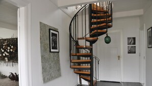 A spiral staircase with wooden steps and black railings, leading to an upper floor.