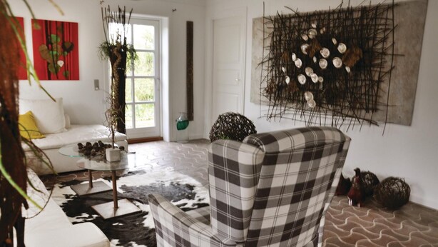 A living room with a plaid armchair, a glass coffee table, and a cowhide rug.
