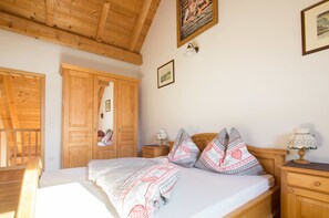 A bedroom with a wooden bed, a wardrobe, a nightstand, and a lamp.