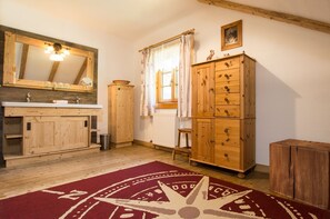 A rustic bathroom with wooden cabinets, a mirror, and a red patterned rug.