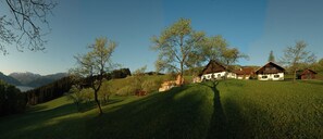 A rural landscape with houses on a hillside, a clear sky, and a lake in the distance.