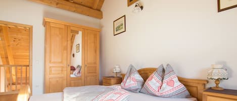 A bedroom with a wooden bed, a wardrobe, a nightstand, and a lamp.