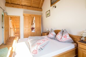 Ein Schlafzimmer mit einem hölzernen Bett, einem Nachttisch, einer Lampe und einer Tür zu einem anderen Raum.