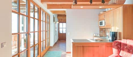 A spacious kitchen with wooden cabinets, a central island, and a dining area with a red sofa.