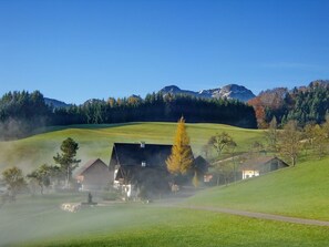 A rural landscape with a farmhouse, a path, and a mountain in the background.