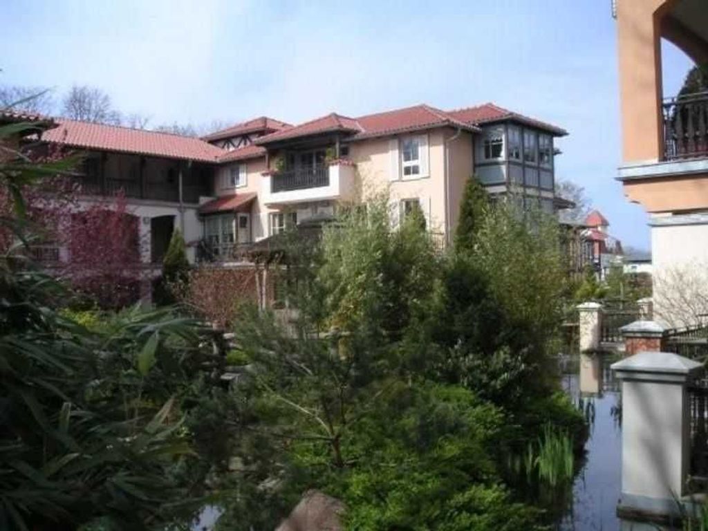 A residential area with multiple two-story houses, a small water body, and lush greenery.