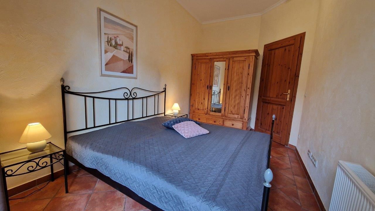 Une chambre à coucher avec un lit, une armoire en bois, une table de chevet avec une lampe et un radiateur.