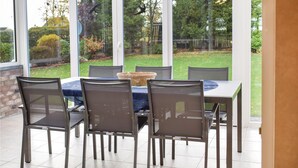 Um pátio com mesa e cadeiras, um cesto e vista para um jardim.