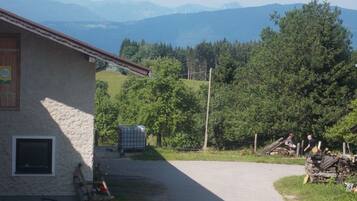 A rural building with a stone exterior, a paved driveway, and a view of mountains.
