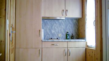 A kitchen with wooden cabinets, a marble countertop, and a window.